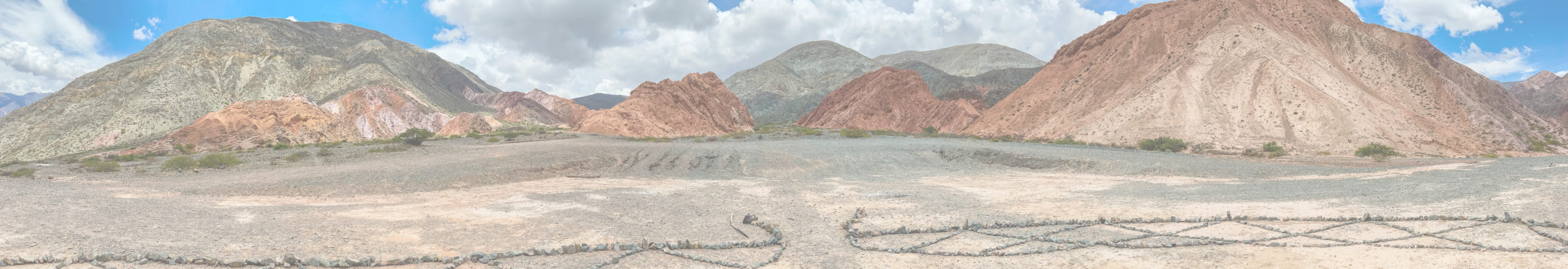 alt="Cerro de los Siete Colores panoramic with mountains in the background“